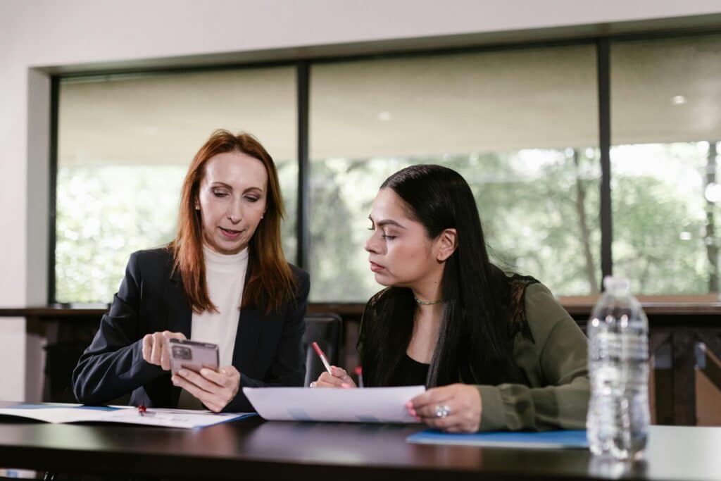 two women review documents in an office setting